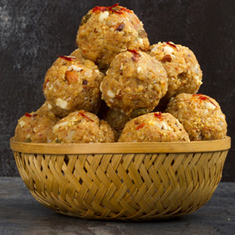 A basket of freshly made cashew sweets with visible toppings of nuts and spices.