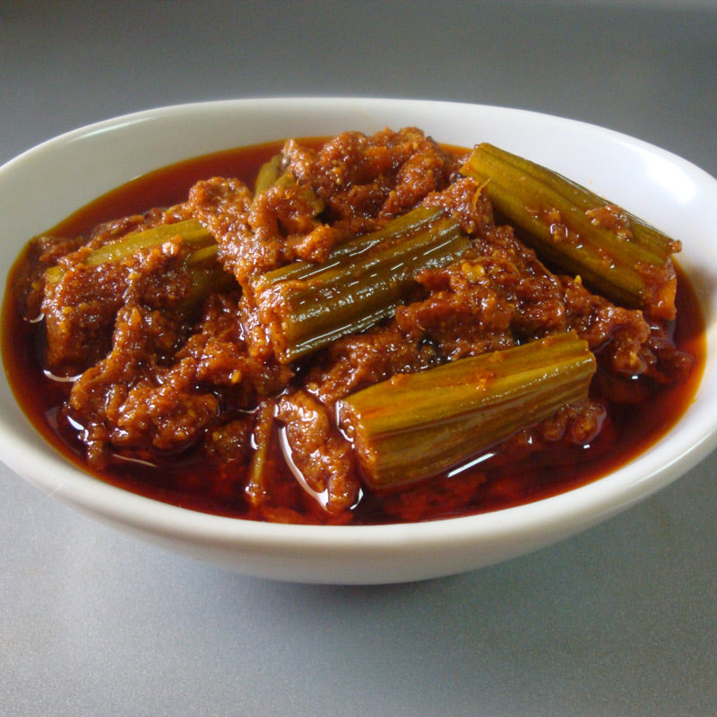 A spicy drumstick pickle, cut into pieces, immersed in a red-colored sauce.