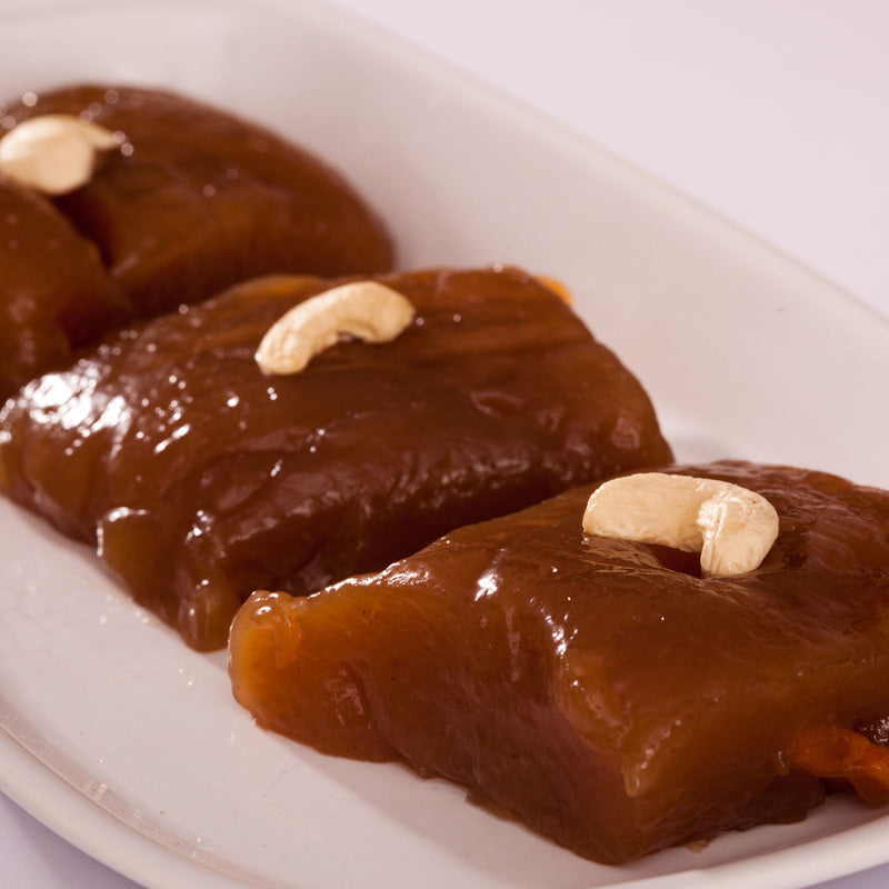cashew sweets (Godhuma Halwa) arranged on a white plate with a nut (cashew) on top of each piece.