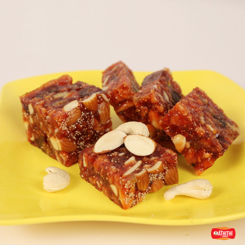 Cashew Sweets Halwa, a rich red-colored dessert with cashewws pieces on a yellow plate.