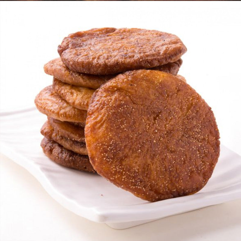Traditional sweet arisalu nuvulu, presented as a stack of round, golden-brown fried sweets on a white plate, with one arisalu partially visible on the plate.