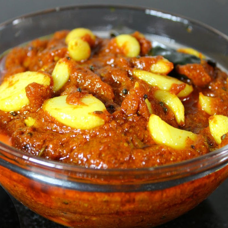 A glass bowl filled with Garlic Pickle, showing chunks of garlic and spices.