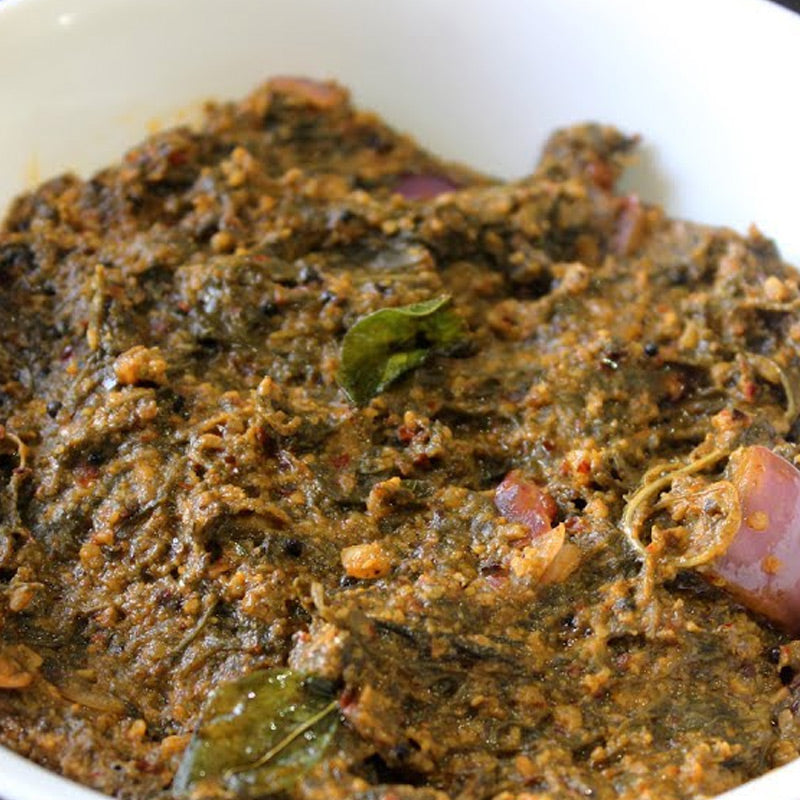 A bowl of Gongurura Roti Pickle, with visible spices and herbs adding a vibrant color to the dish.